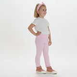 Mädchen in pinken Leggings und weißem T-Shirt, präsentiert das Schnittmuster Hoodie und Leggings ARWEN für Größen von 12 M bis 11 J.