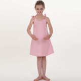 Schnittmuster Schürzenkleid JULE PDF 3-in-1, Mädchen im rosa Schürzenkleid mit Schleifen, ideal für Kindergrößen 74/80–146/152.