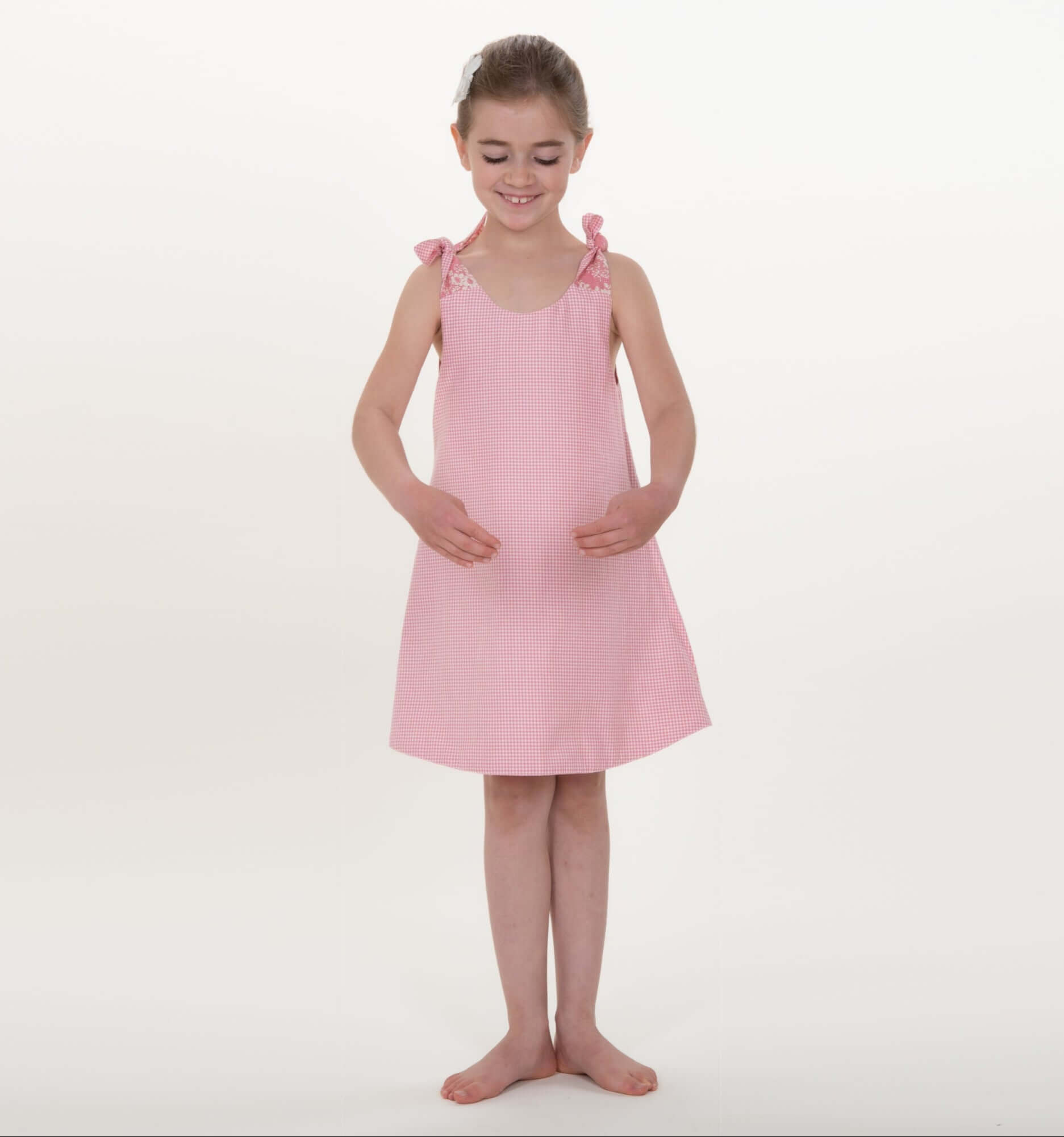Schnittmuster Schürzenkleid JULE PDF 3-in-1, Mädchen im rosa Schürzenkleid mit Schleifen, ideal für Kindergrößen 74/80–146/152.