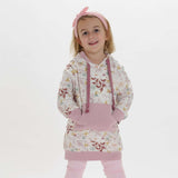 Schnittmuster Tunika Hoodie ARWEN: Mädchen trägt einen floral bedruckten Tunika Hoodie in Rosa.