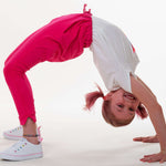 Schnittmuster Set für einen fröhlichen, aktiven Jungen im pinken Outfit und T-Shirt, das einen Handstand macht.