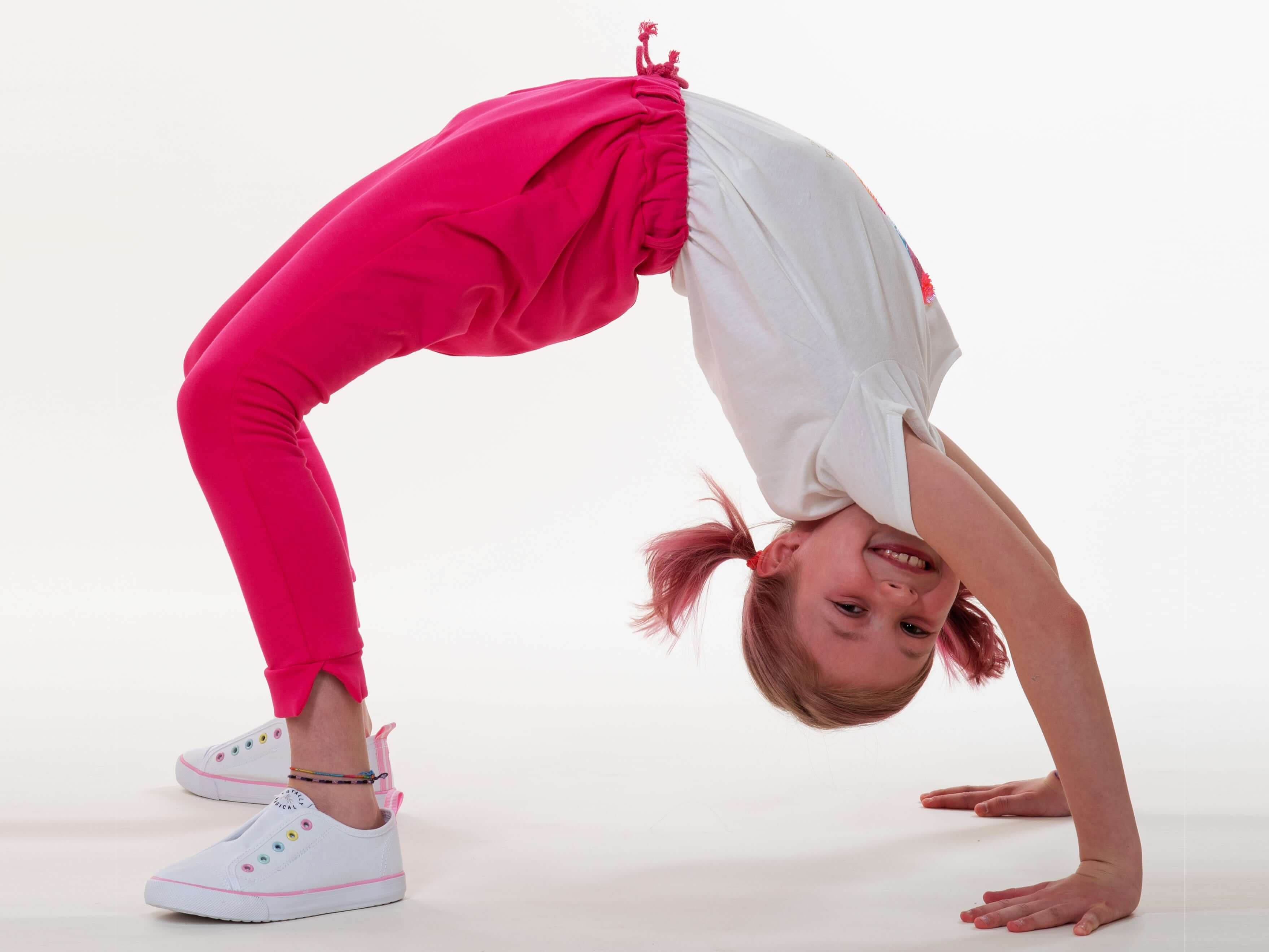 Schnittmuster Set für einen fröhlichen, aktiven Jungen im pinken Outfit und T-Shirt, das einen Handstand macht.