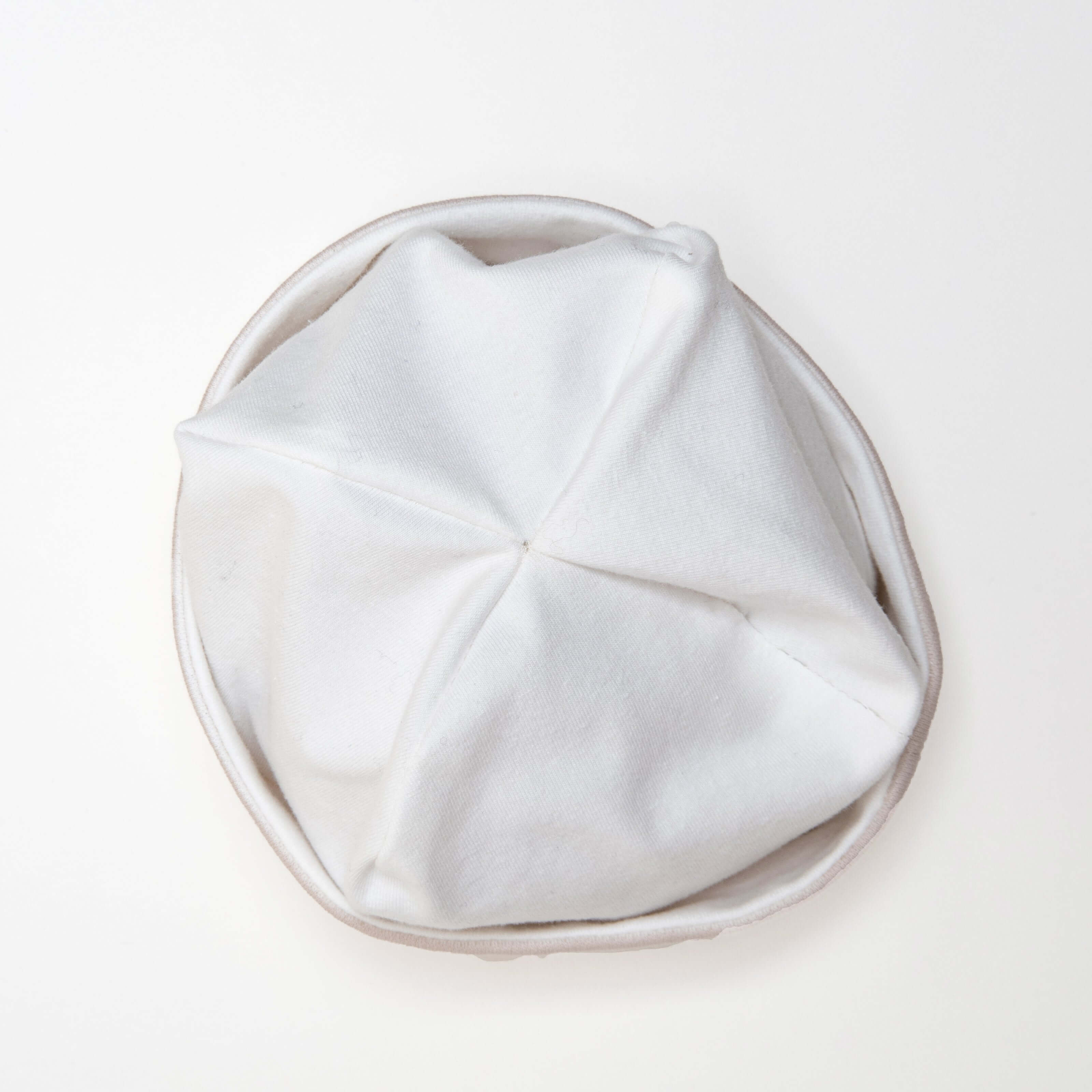 Schnittmuster Set Baby Strampler und Mütze, weiße Baby-Mütze, obenansicht des Mützendesigns aus weichem Stoff.