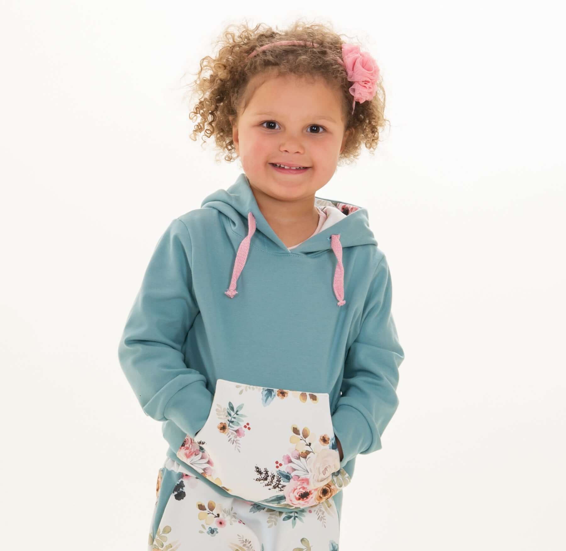 Schnittmuster Hoodie FLY PDF 2-in-1 Kapuze Schalkragen, kindliches Model in buntem Hoodie mit Blumenmuster.
