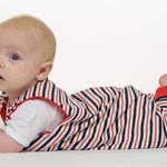 Baby in gestreiftem Strampler liegt auf dem Bauch, trägt das Schnittmuster Strampler LEO.