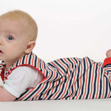 Baby in gestreiftem Strampler liegt auf dem Bauch, trägt das Schnittmuster Strampler LEO.