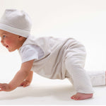 Schnittmuster Set Baby Strampler und Mütze in Verwendung, Baby mit gestreiftem Strampler und Mütze, crawlt spielerisch.
