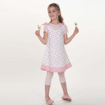 Mädchen trägt ein Schürzenkleid nach dem Schnittmuster Schürzenkleid JULE PDF 3-in-1 mit Blumenmuster.