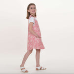Schnittmuster Schürzenkleid Mädchen trägt ein rosa Schürzenkleid, das nach Schnittmuster Schürzenkleid JULE PDF 3-in-1 genäht wurde.
