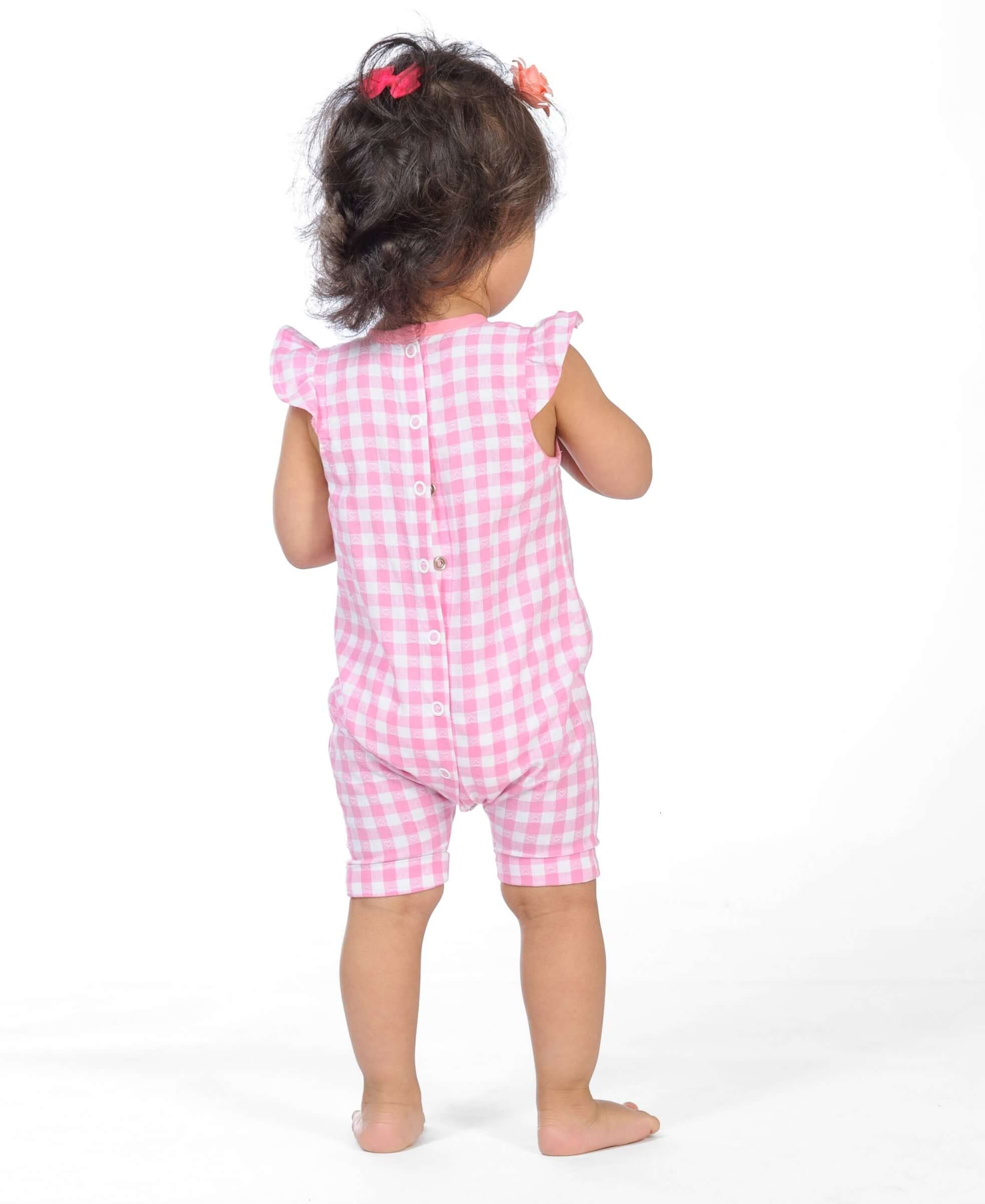 Schnittmuster Baby Overall MIA – Baby und Kleinkind Sommer-Jumpsuit in Pink mit Volant Ärmel und Druckknopf Verschluss.
