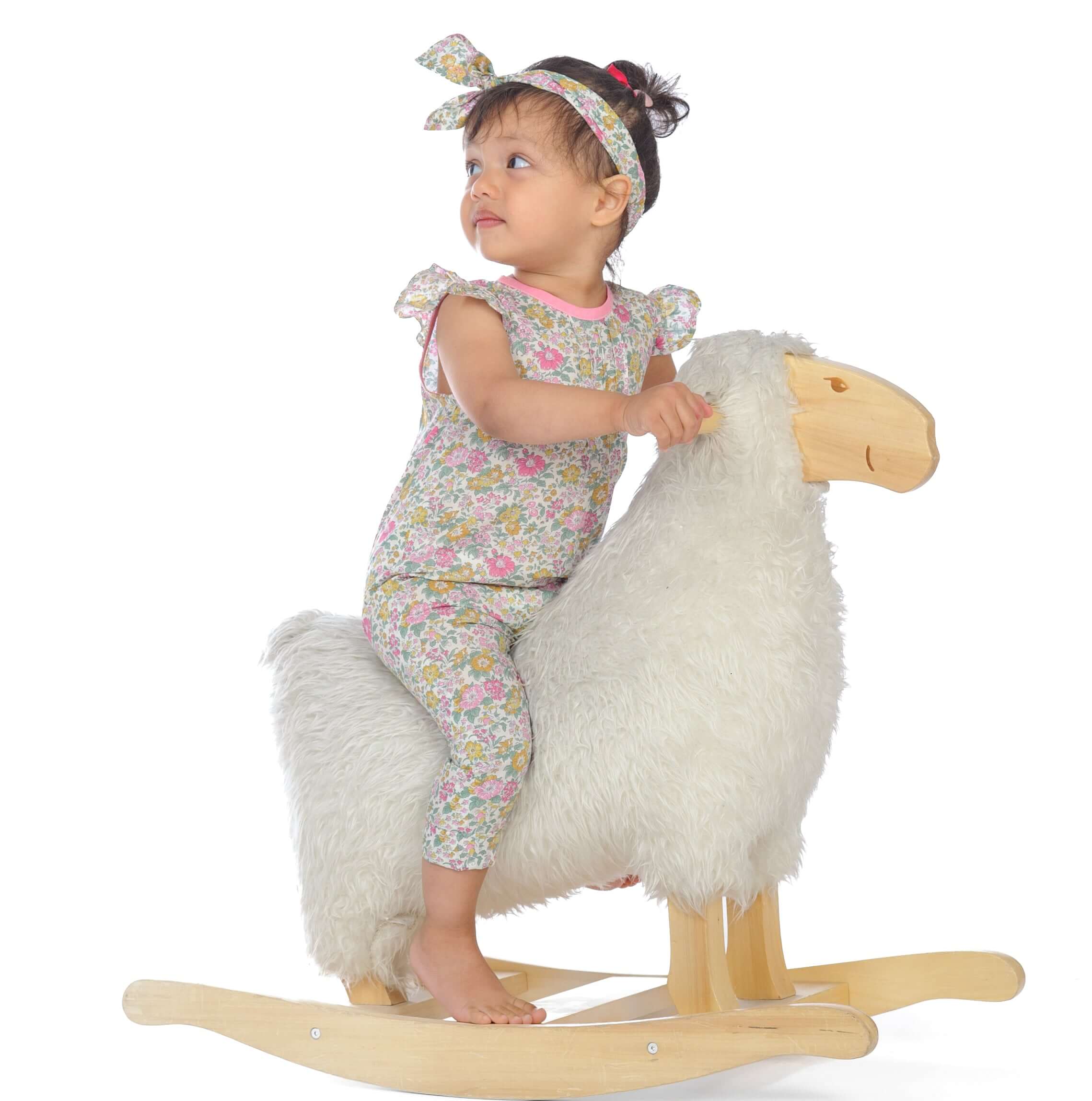 Schnittmuster Baby Overall MIA Jumpsuit, auf einem Schaukelpferd sitzend, mit Haarband.