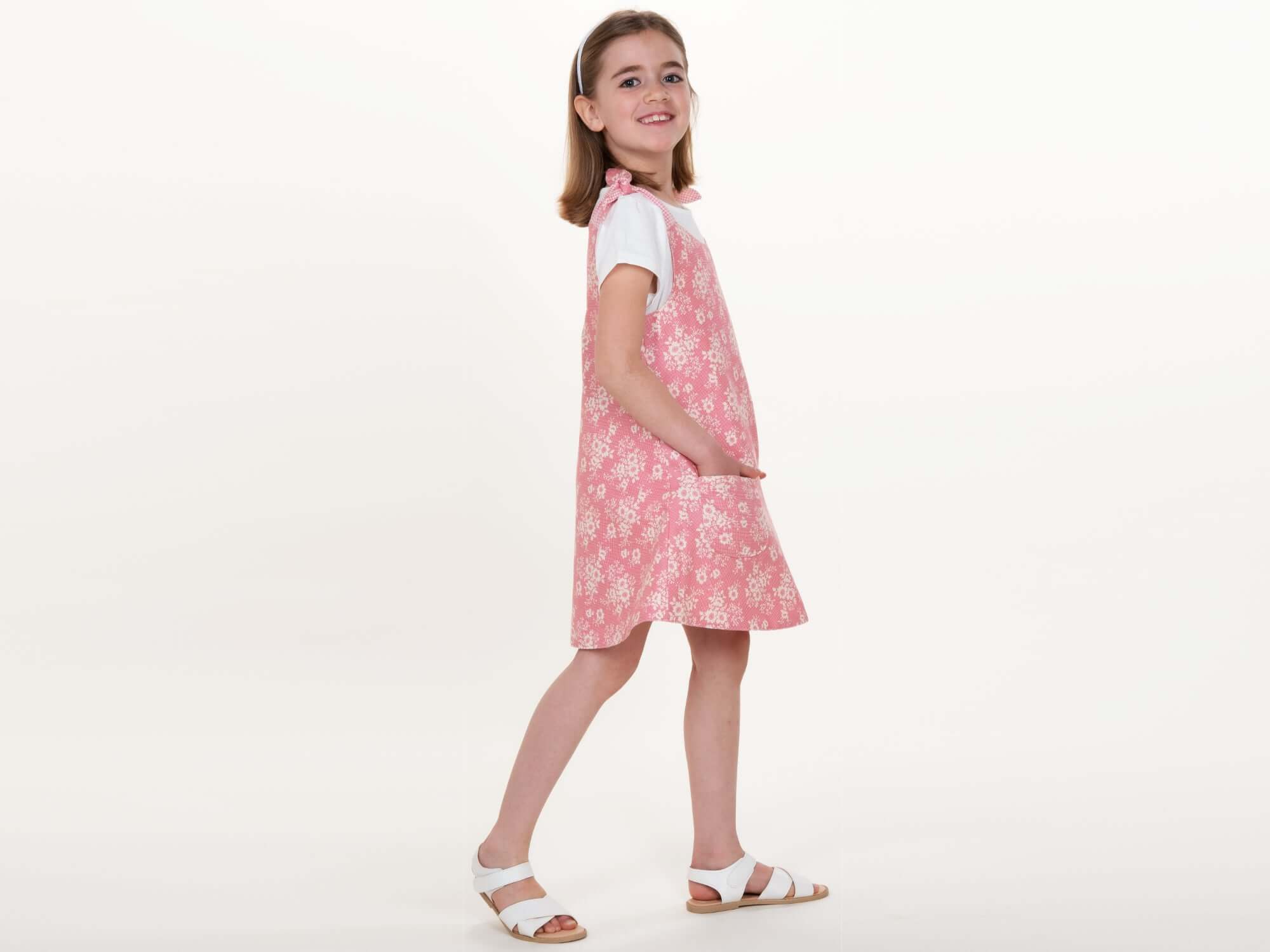 Schnittmuster Mädchenkleid STEFFI Gr. 74 - 152 präsentiert ein pinkes Kleid mit Blumenmuster, perfekt für den Sommer.