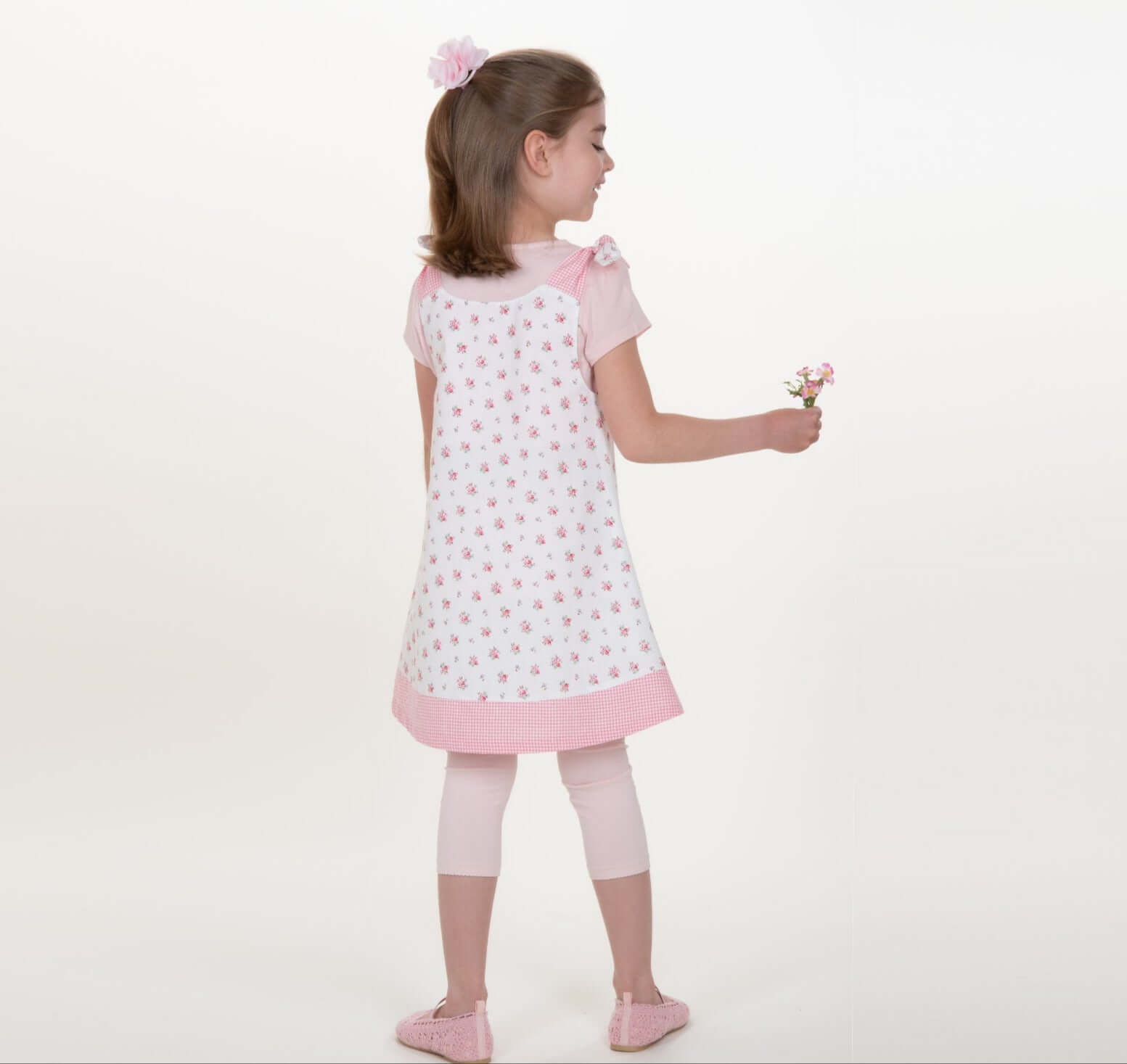 Schnittmuster Schürzenkleid JULE PDF 3-in-1, Mädchen im Schürzenkleid mit Blumenmuster und Leggings.
