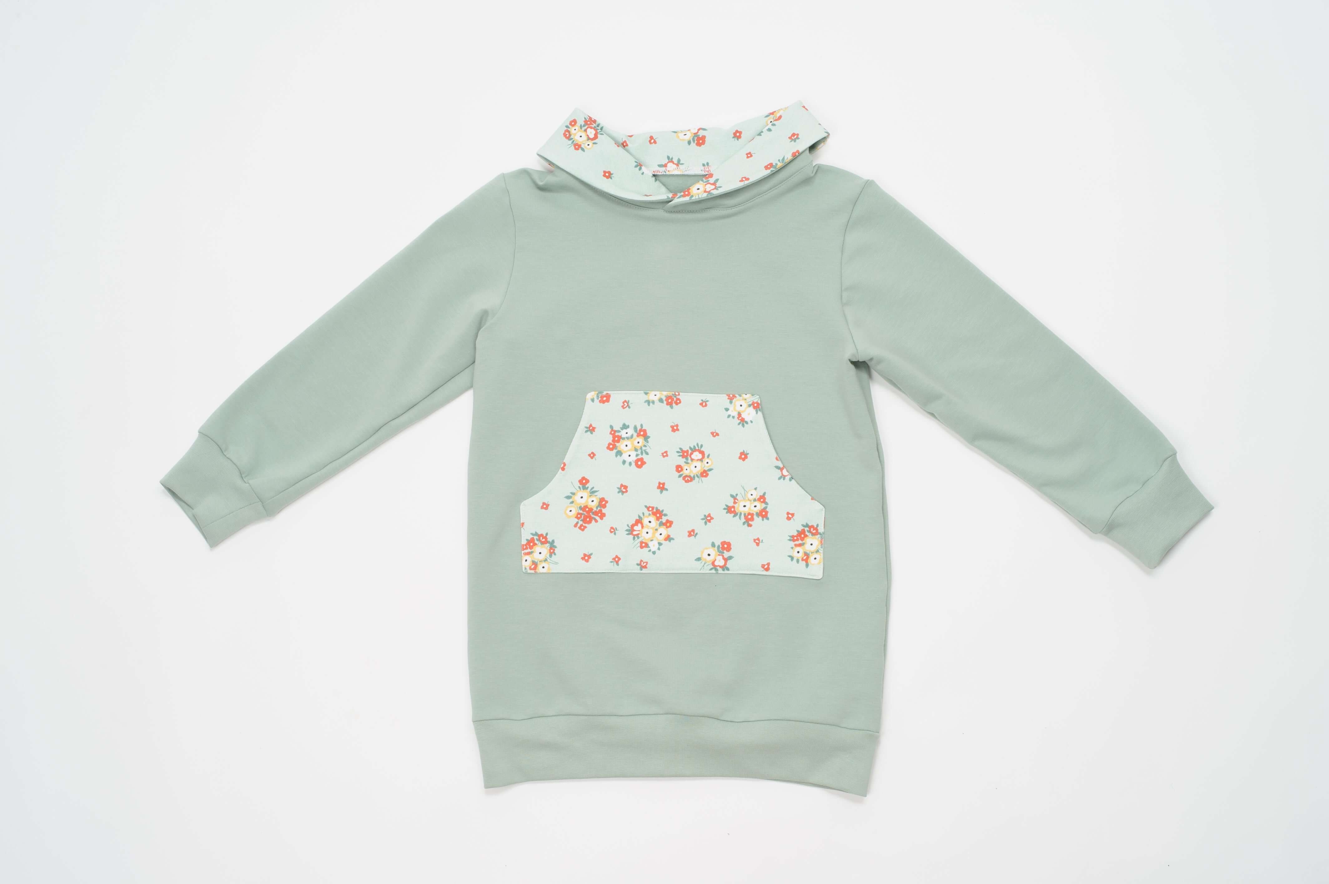 Schnittmuster Mädchen Tunika Hoodie ARWEN in sanftem Grün mit Blumenmuster und bequemer Passform.