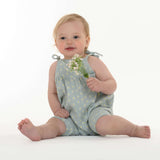 Schnittmuster Baby Overall Jumpsuit NELE – Kleinkind im blauen Overall mit Blumen, sitzend und lächelnd.