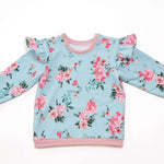 Schnittmuster Baby Sweatshirt mit floralen Mustern, Rüschenärmeln und rosa Details für stilvolle Babykleidung.