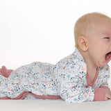 Schnittmuster Strampler LISA PDF Baby: Baby im bunten Strampler mit floralem Muster, schläft und gähnt.