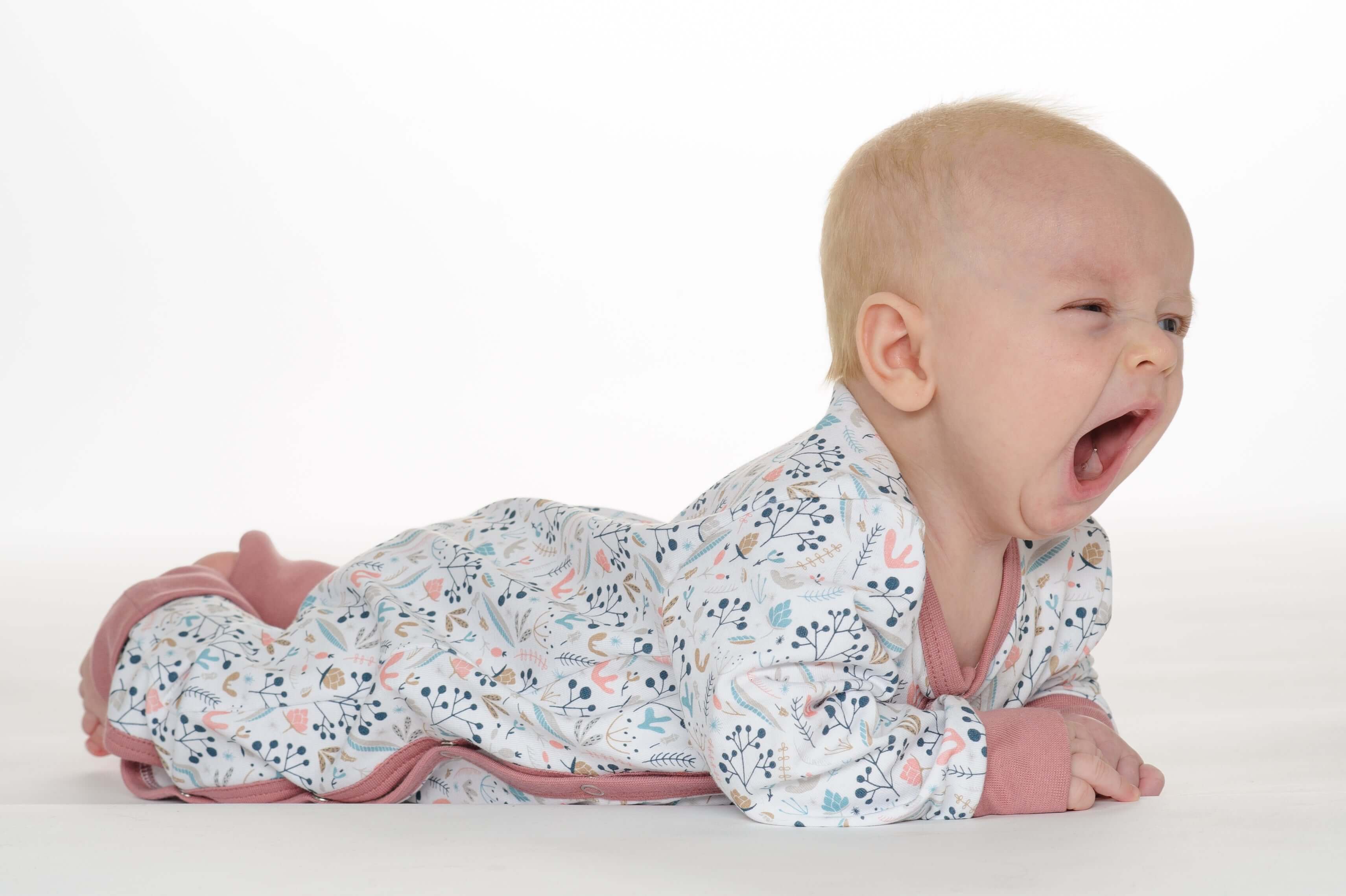 Schnittmuster Strampler LISA PDF Baby: Baby im bunten Strampler mit floralem Muster, schläft und gähnt.