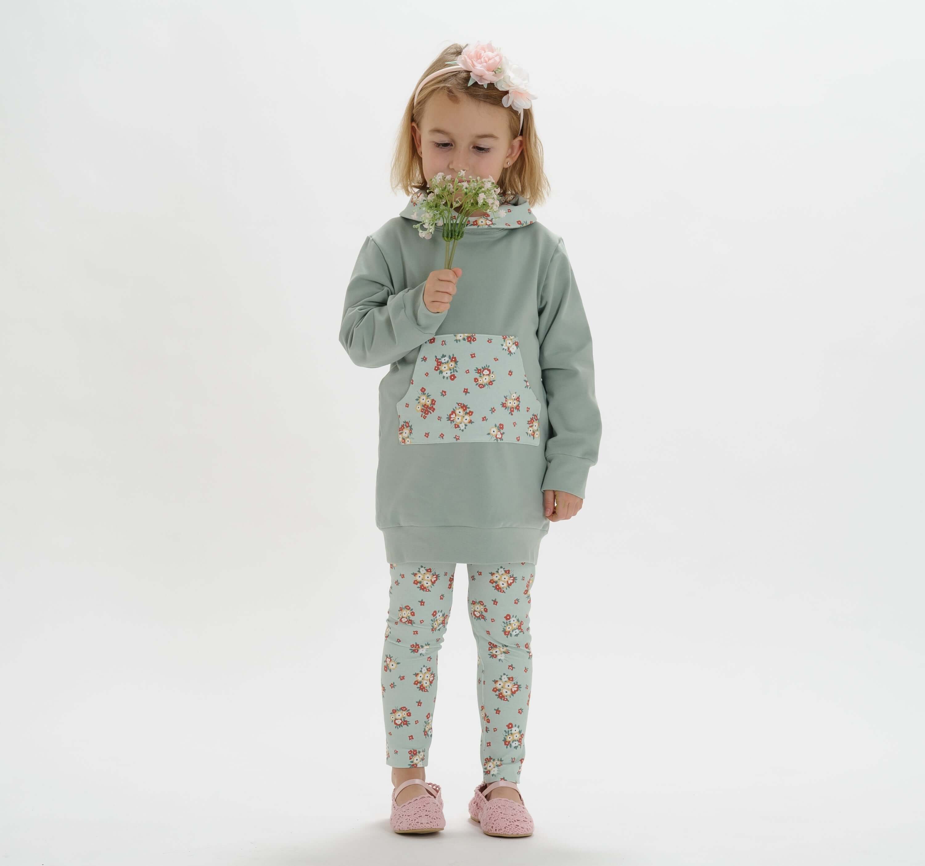 Schnittmuster Mädchen Tunika Hoodie ARWEN PDF - Mädchen in mintgrüner Tunika mit Blütenmuster und Leggings.