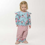 Schnittmuster Baby Sweatshirt in blauer Blüten-Optik, getragen von einem kleinen Mädchen mit rosa Hosen.