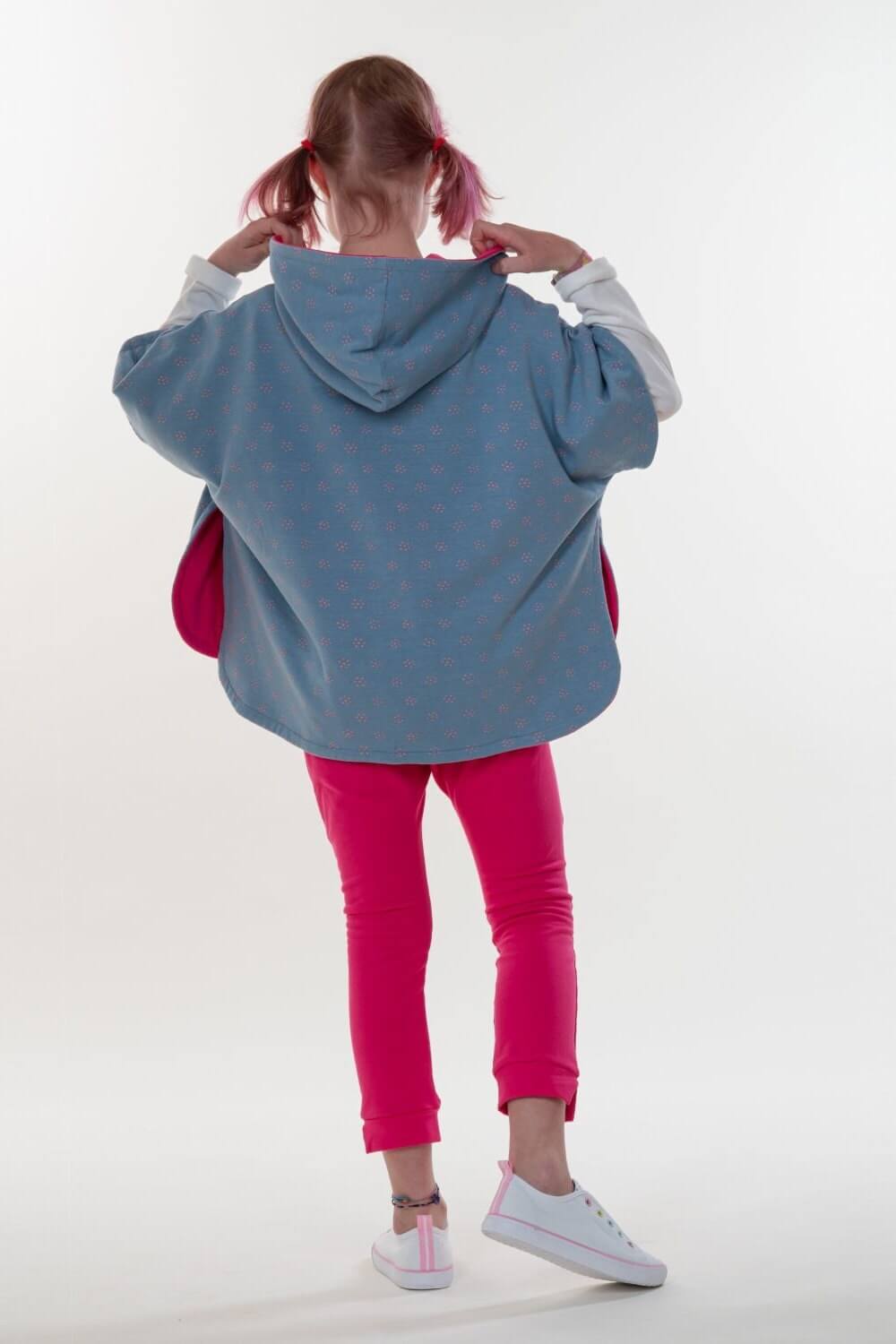 Schnittmuster Mädchen Poncho PAULA in blauem gepunktetem Design mit Kapuze, für Kinder, Rückansicht.
