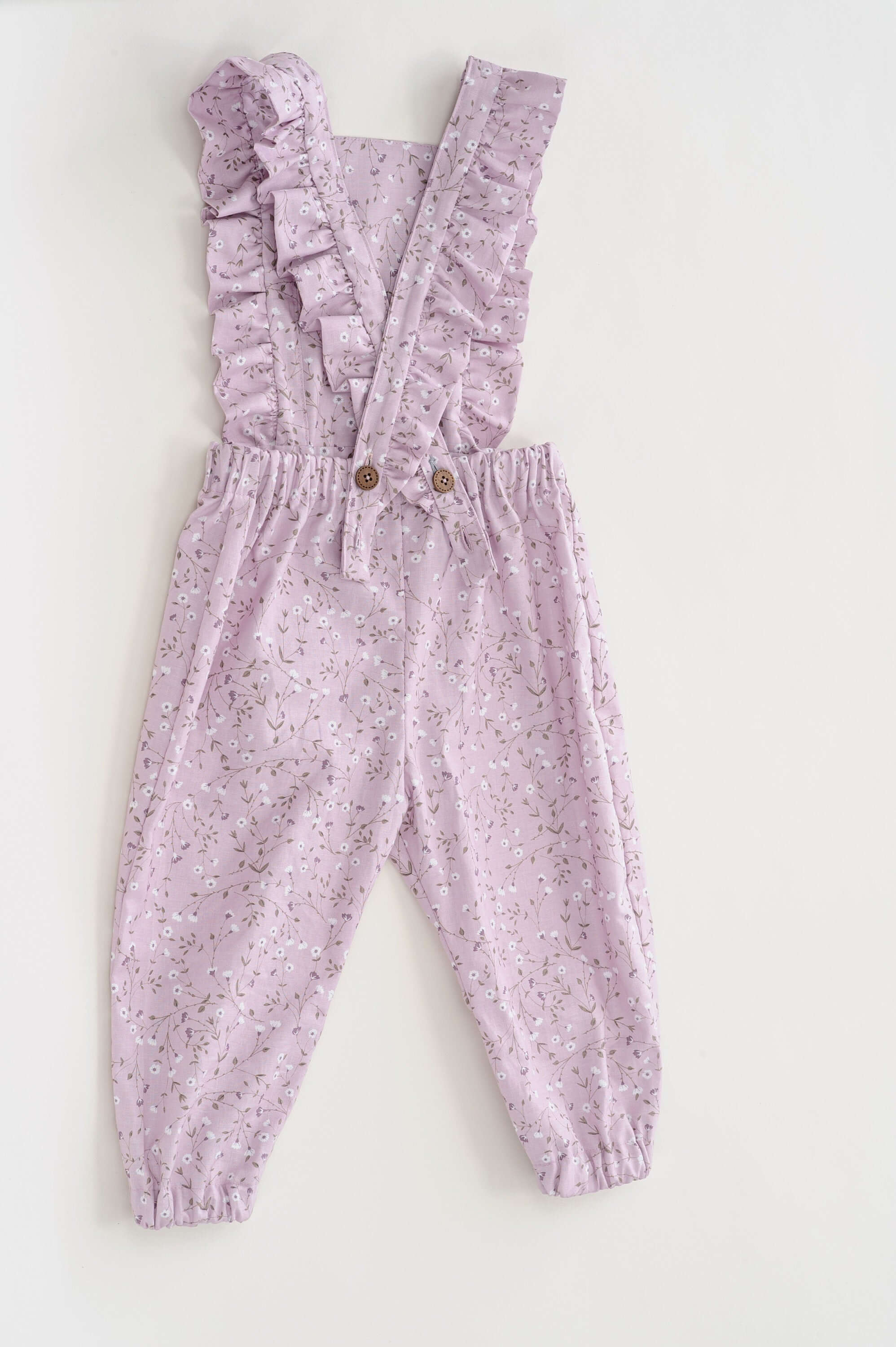 Schnittmuster Latzhose DAISY in zartem Lila mit Rüschen und elastischem Bund, ideal für Kinder von 6 Monaten bis 7 Jahren.