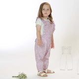 Schnittmuster Latzhose DAISY PDF in rosa für Kinder, Größen 68/74-116/122, mit Rüschen und gekreuzten Trägern.