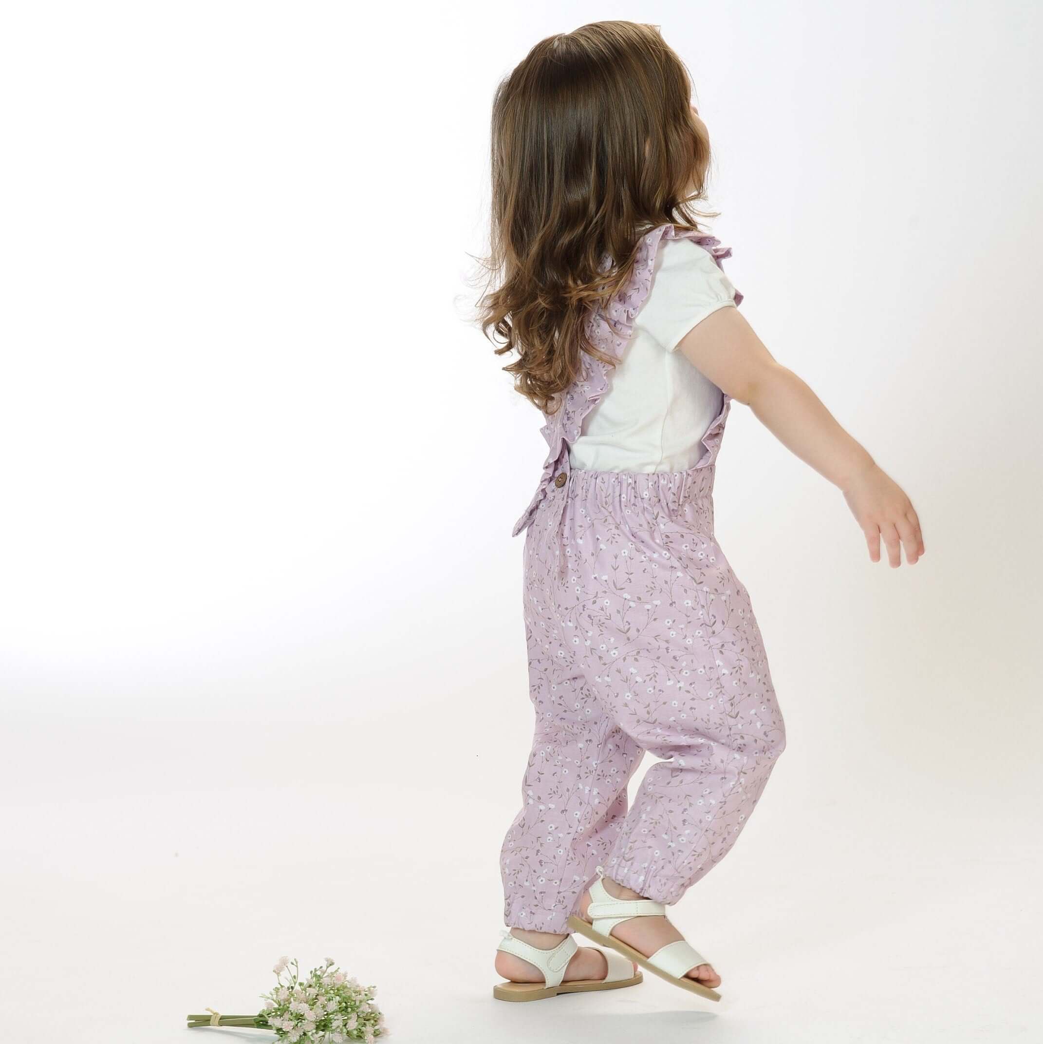 Schnittmuster Latzhose DAISY PDF mit Rüschen, einjähriges Kind in lila Latzhose, perfektes Nähprojekt für kleine Mädchen.