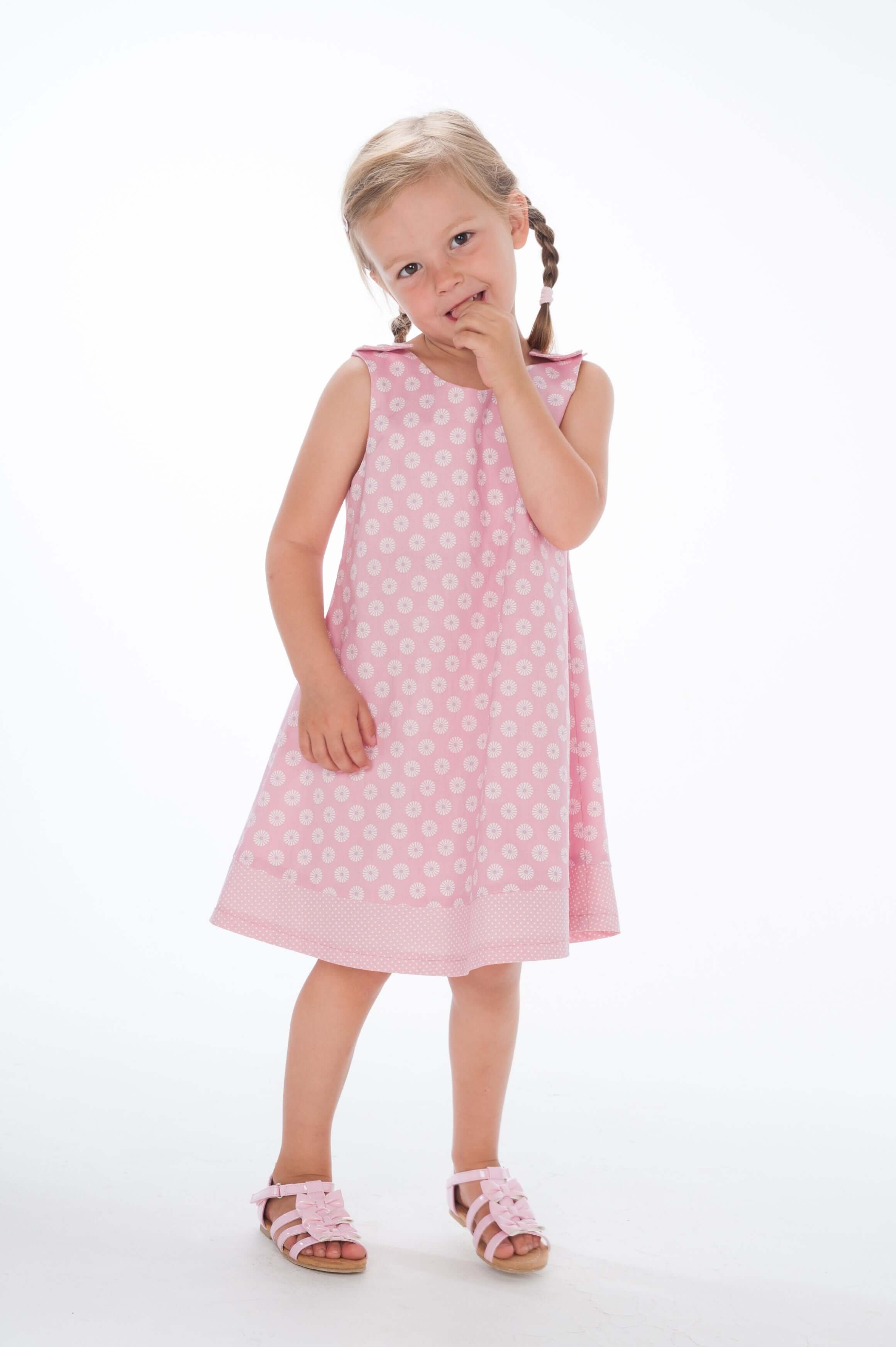 Süßes Mädchen trägt ein pinkes Schürzenkleid, inspiriert vom Schnittmuster Schürzenkleid JULE PDF 3-in-1.