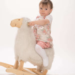 Schnittmuster Baby Twinset Babykleid Hängerchen und Pumphose, Baby auf einem Holz-Schaukel-Schaf mit einem blumigen Kleid.