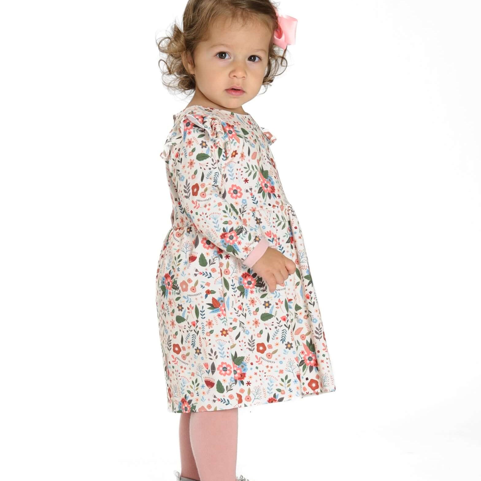 Schnittmuster Retro Kleid für Mädchen ELLA mit langen Ärmeln, gezeigt an einem Mädchen mit Blumenmuster.